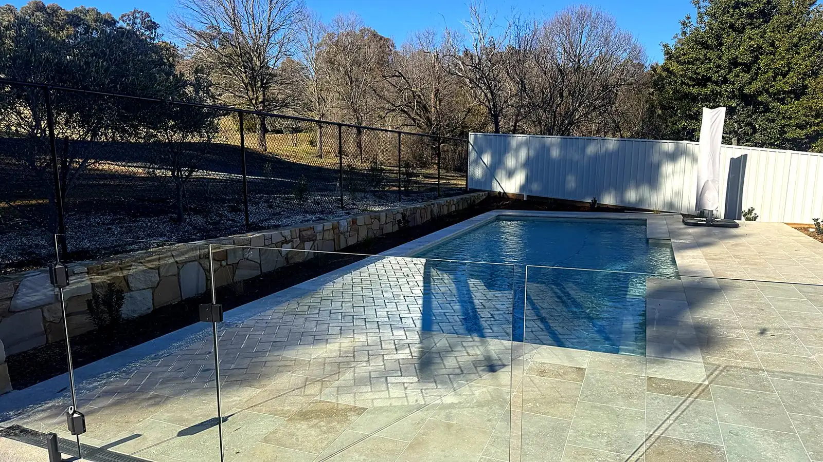 Glass pool barrier around a lap pool with a rural Canberra outlook